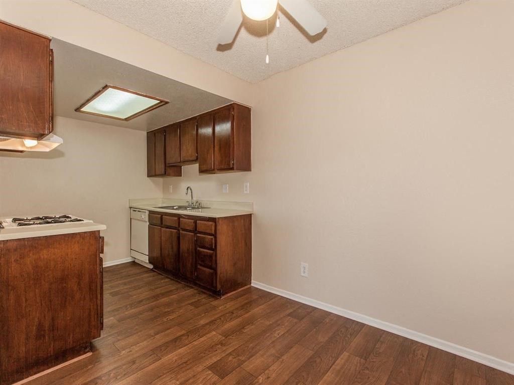 an empty kitchen with wood flooring and a ceiling fan