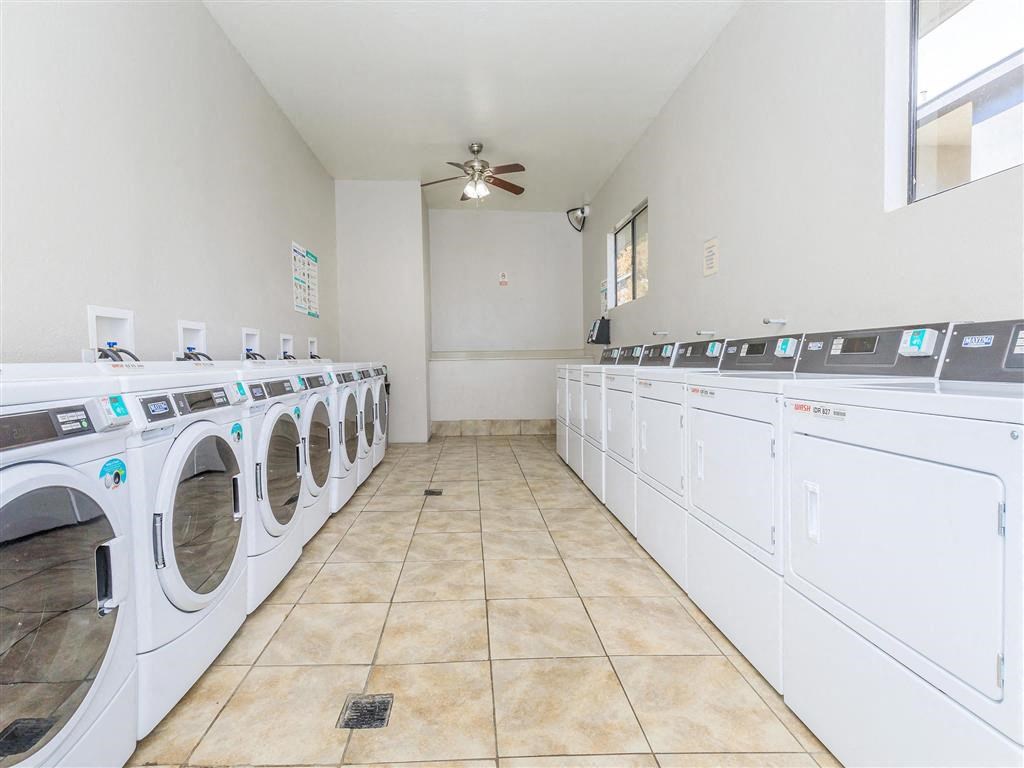 a washer and dryer room with lots of washing machines and a ceiling fan