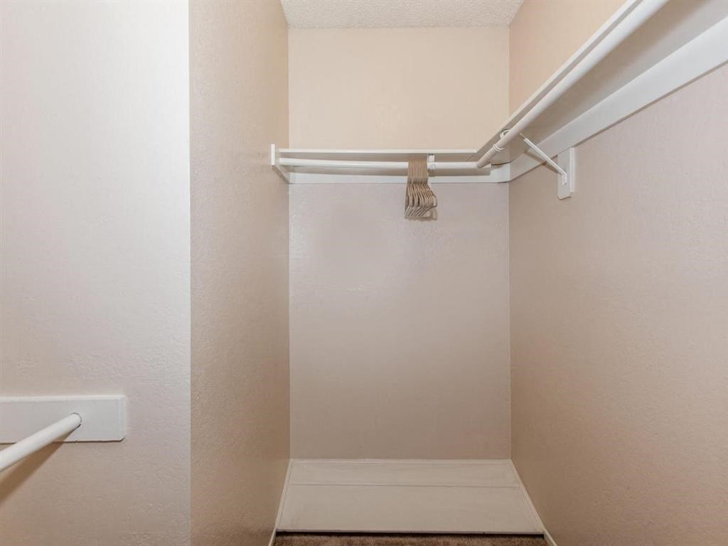 an empty walk in closet in a bathroom with a white shower curtain