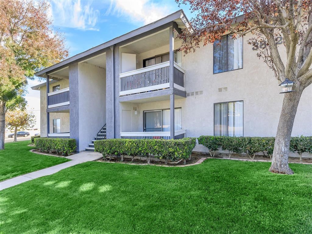 an apartment building with a lawn and trees in front of it
