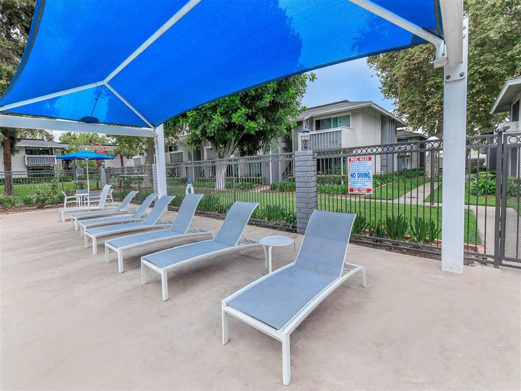 a row of blue lounge chairs under a blue canopy