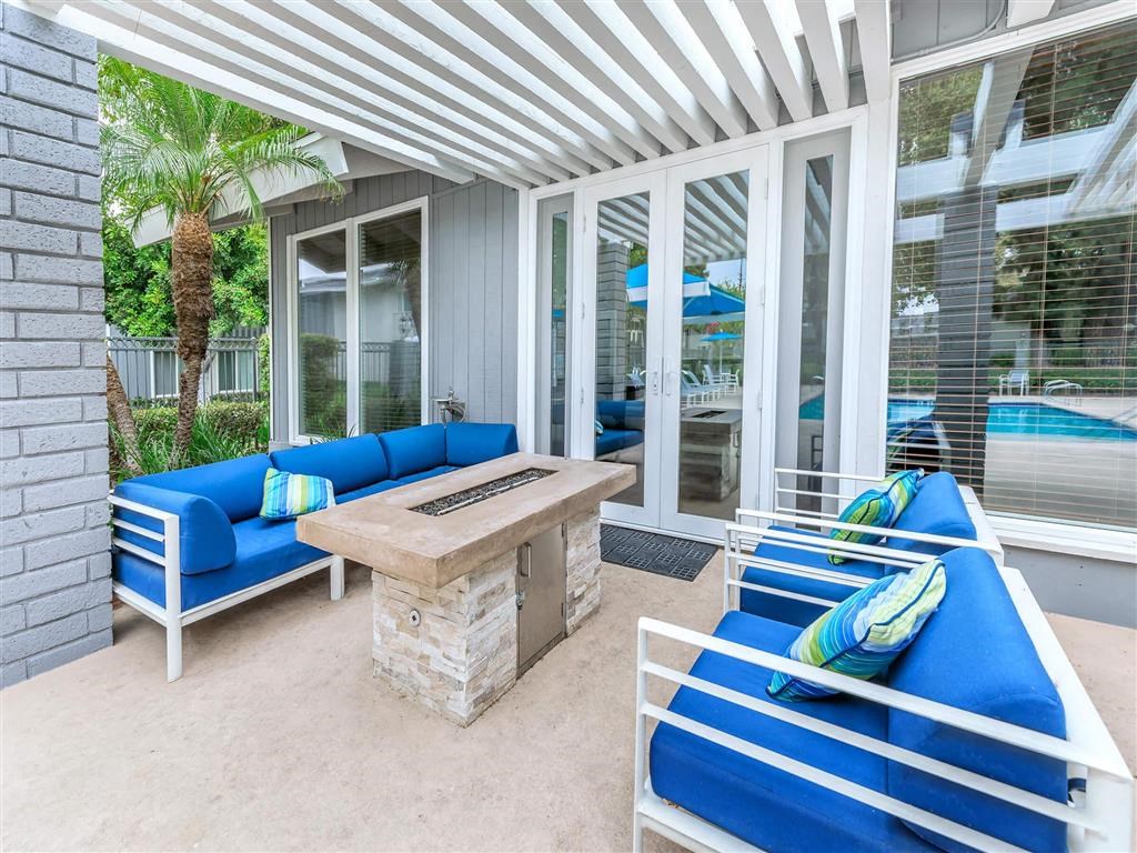a covered patio with a fire pit and couches and a table