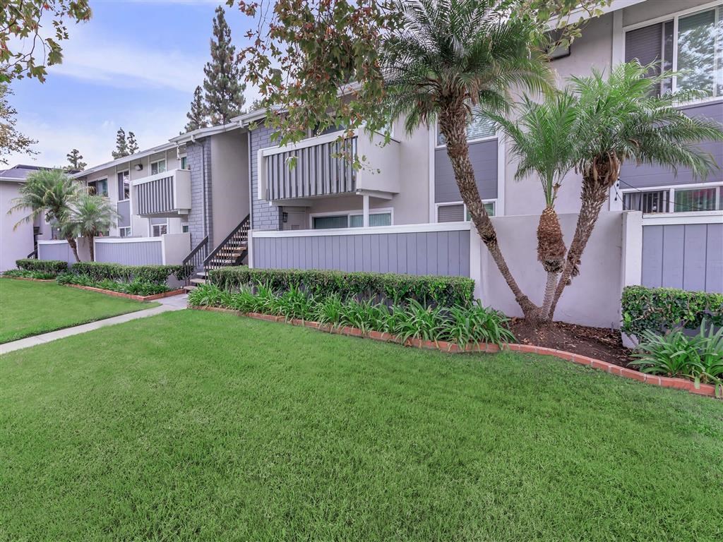 a yard in front of an apartment building with palm trees