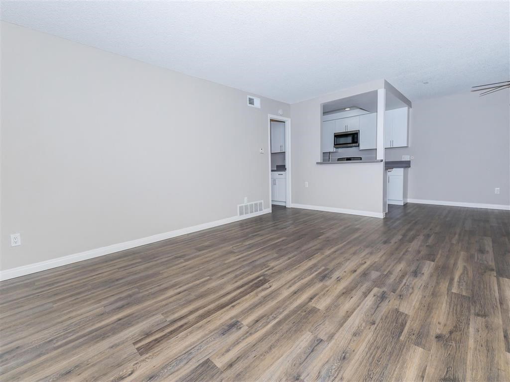 the living room and kitchen of an apartment with wood flooring