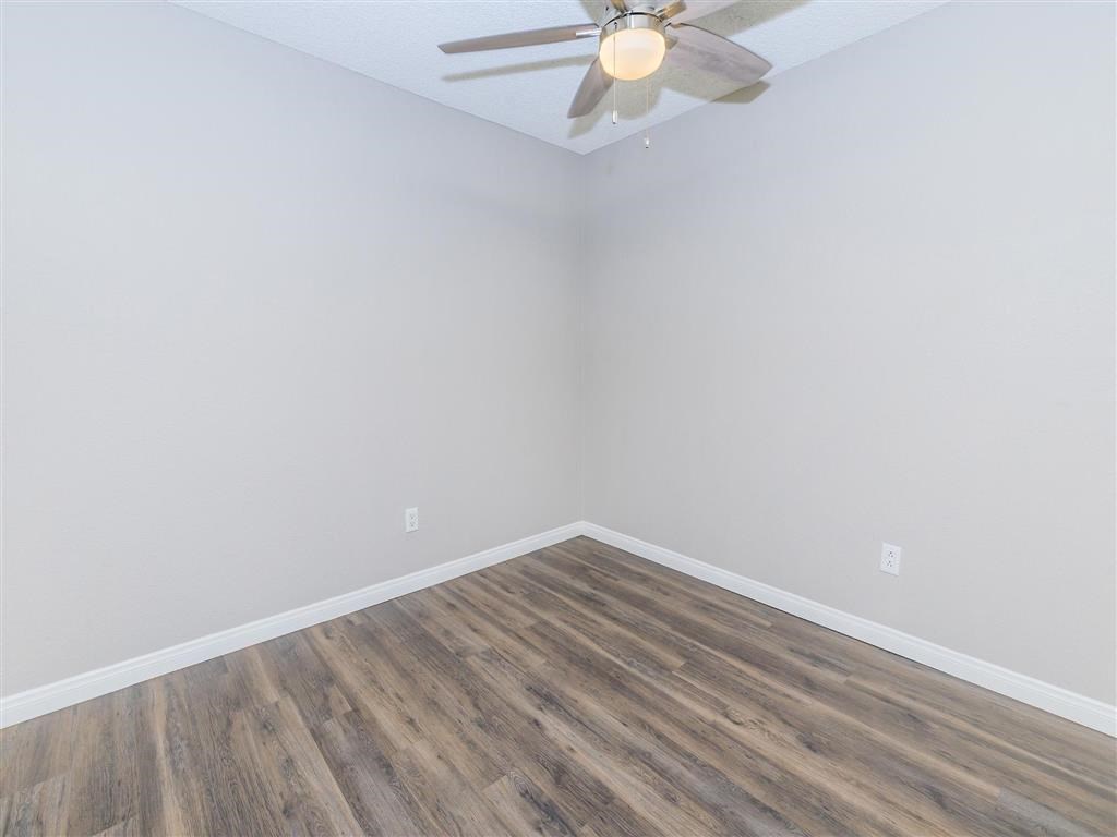 an empty room with wood flooring and a ceiling fan