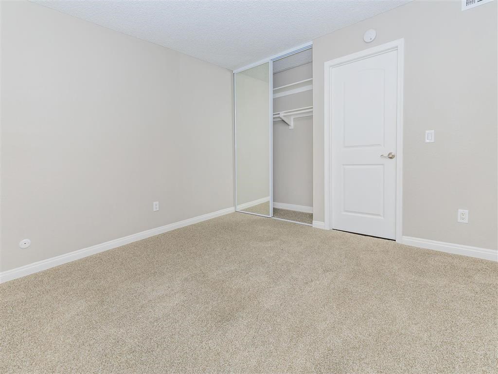 an empty bedroom with a closet and a white door