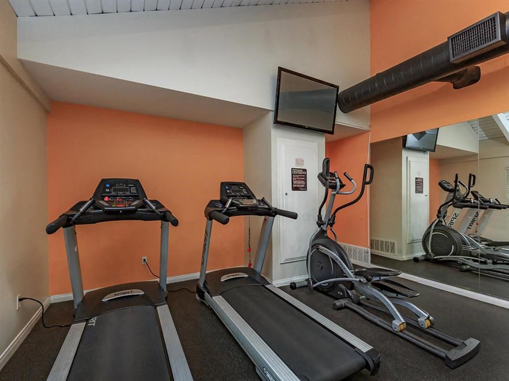 two treadmills and a tv in a workout room
