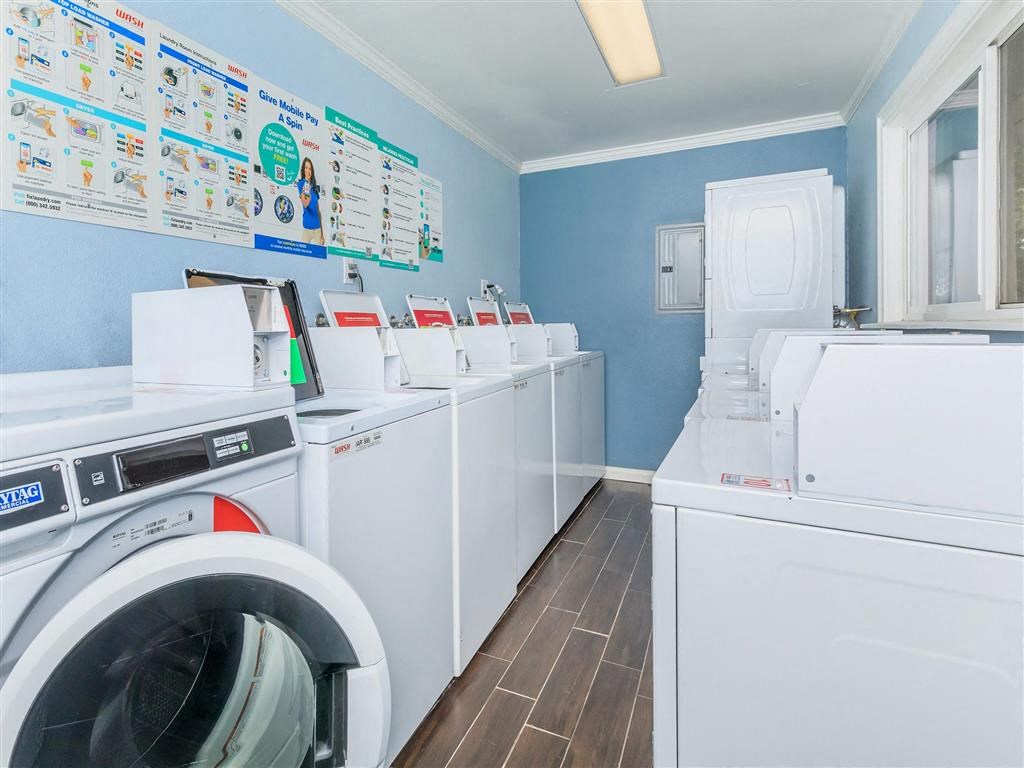 a washer and dryer in a laundry room with a row of washing machines