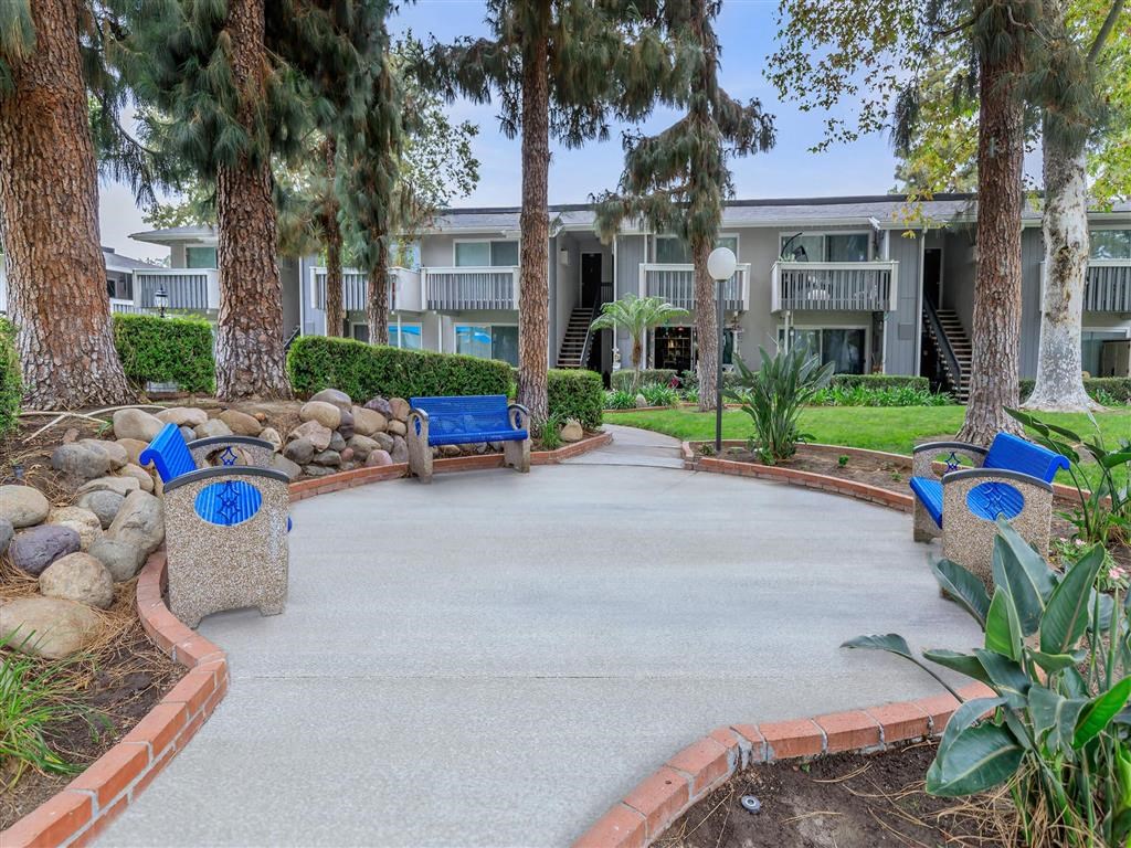 a courtyard with benches and trees in front of an apartment building