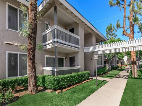 a sidewalk in front of an apartment building with a balcony