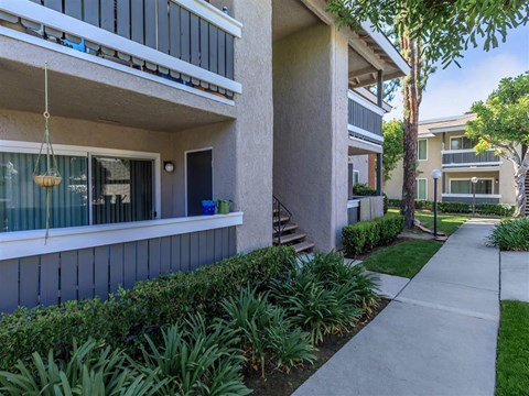 a sidewalk in front of a building with trees and plants