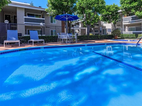 a large blue pool with chairs and an umbrella
