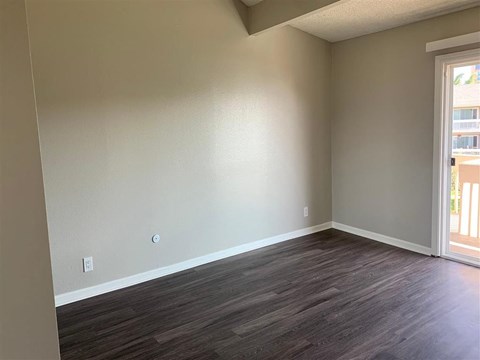 A room with wooden flooring and a door leading outside.