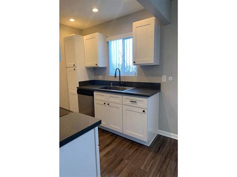 A kitchen with white cabinets and a black countertop.