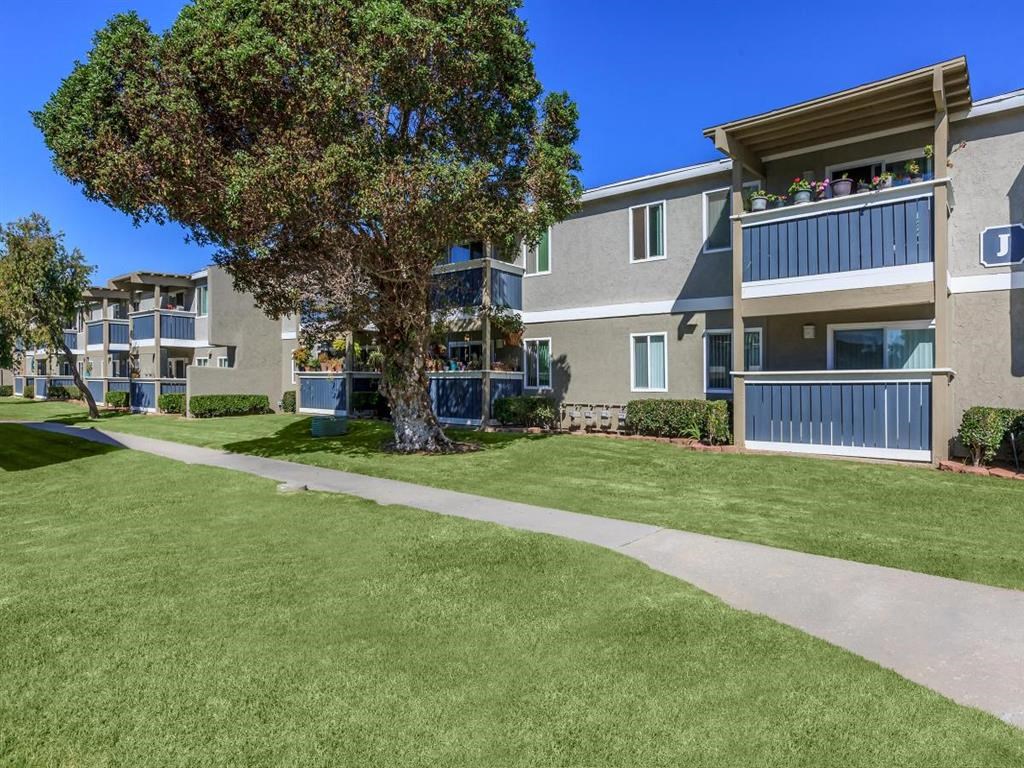 an exterior view of an apartment building with a sidewalk and lawn