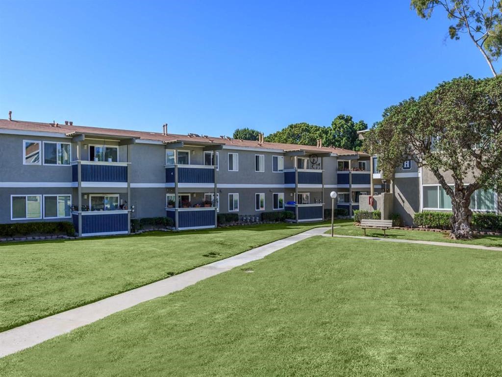 an exterior view of an apartment building with a lawn and sidewalk
