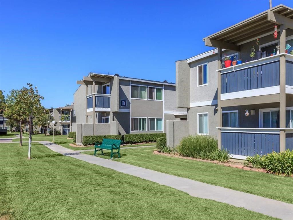 a green park bench in front of some apartments