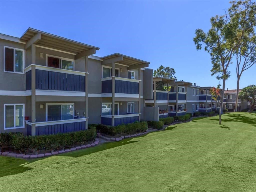 an exterior view of an apartment complex with a large grass field