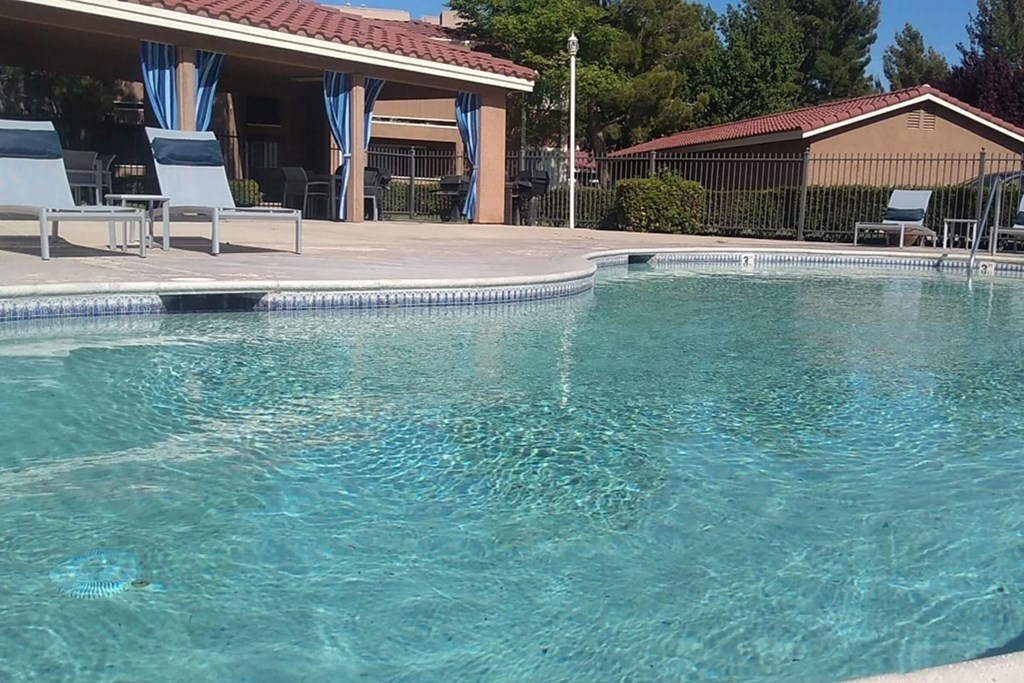 a swimming pool with chairs and a house in the background