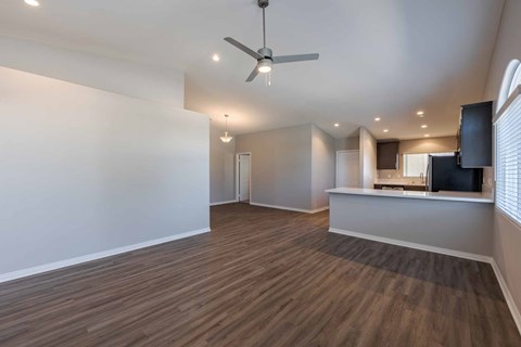 A spacious room with a ceiling fan and wooden flooring.