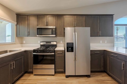 A kitchen with a stove, refrigerator, and microwave.