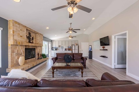 A living room with a brown leather couch and a fireplace.