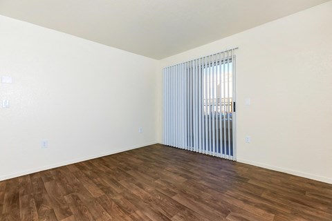 an empty living room with wood flooring and a window