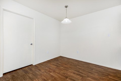 a bedroom with white walls and wood flooring and a closet