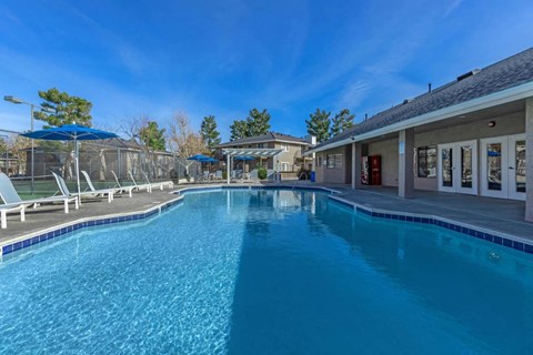 A large swimming pool with a blue tiled edge and a building in the background.