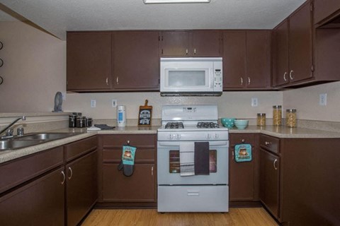 A kitchen with brown cabinets and a white stove top oven.
