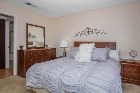 A bedroom with a large bed and a dresser with a mirror above it.