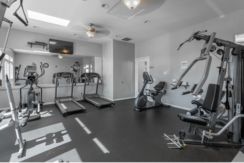 a gym with treadmills and other exercise equipment and a tv