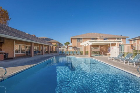 A swimming pool in front of a building with a clear blue sky.