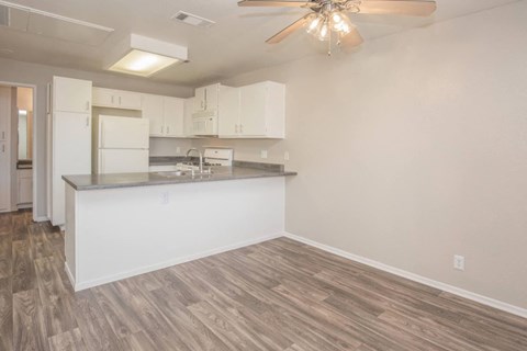 A kitchen with white cabinets and a wooden floor.