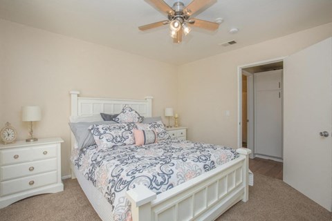 A bedroom with a bed, dresser, and ceiling fan.