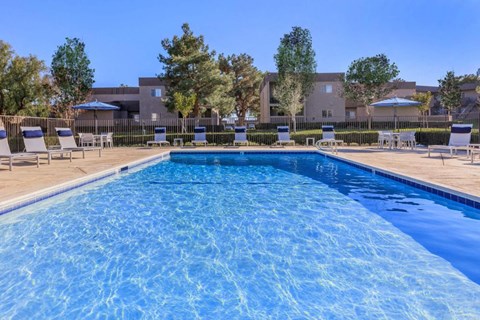 A swimming pool surrounded by lounge chairs and trees.