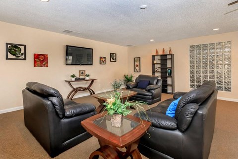 A living room with black leather couches and a wooden coffee table.
