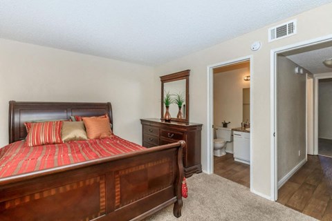 A bedroom with a large bed and a dresser with a mirror.