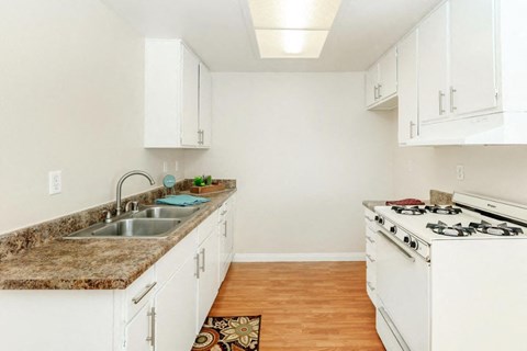 A kitchen with white cabinets and a granite countertop.