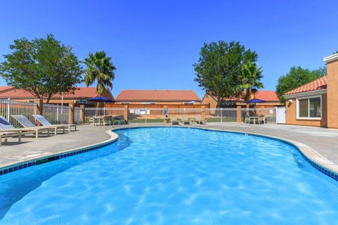 A large outdoor swimming pool surrounded by a fence and trees.
