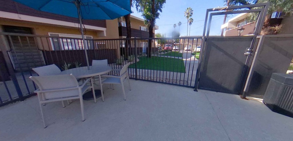 a patio with a table and chairs and a fence