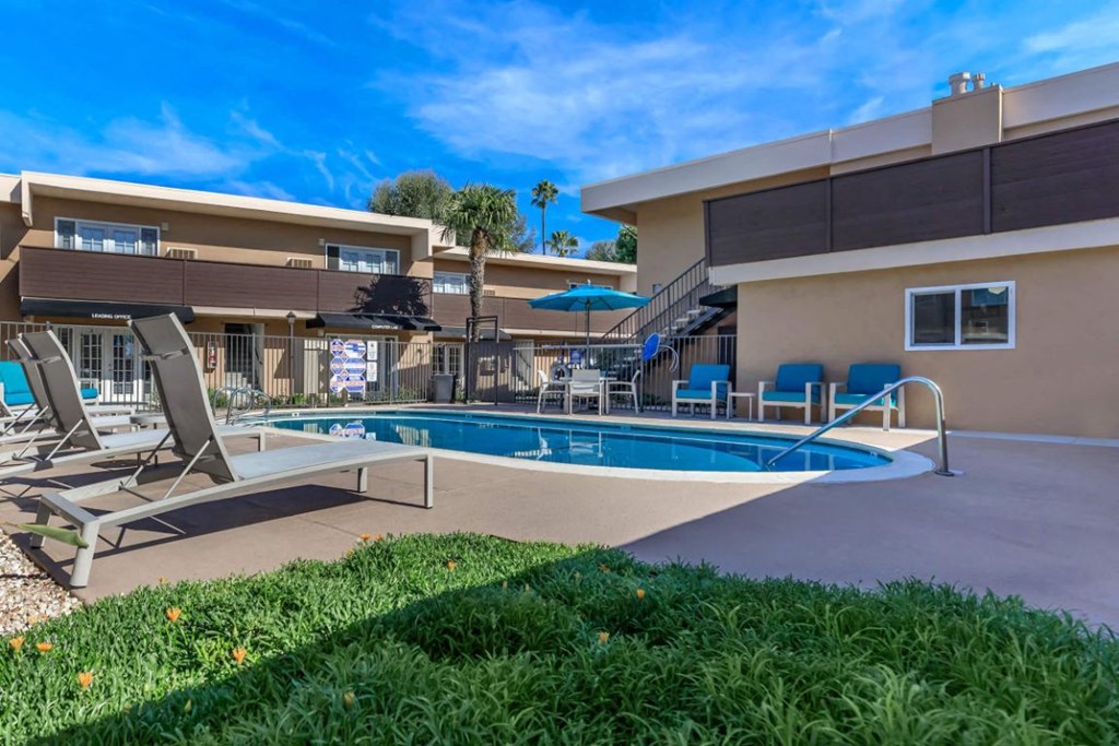 a swimming pool with chairs and umbrellas in front of a building