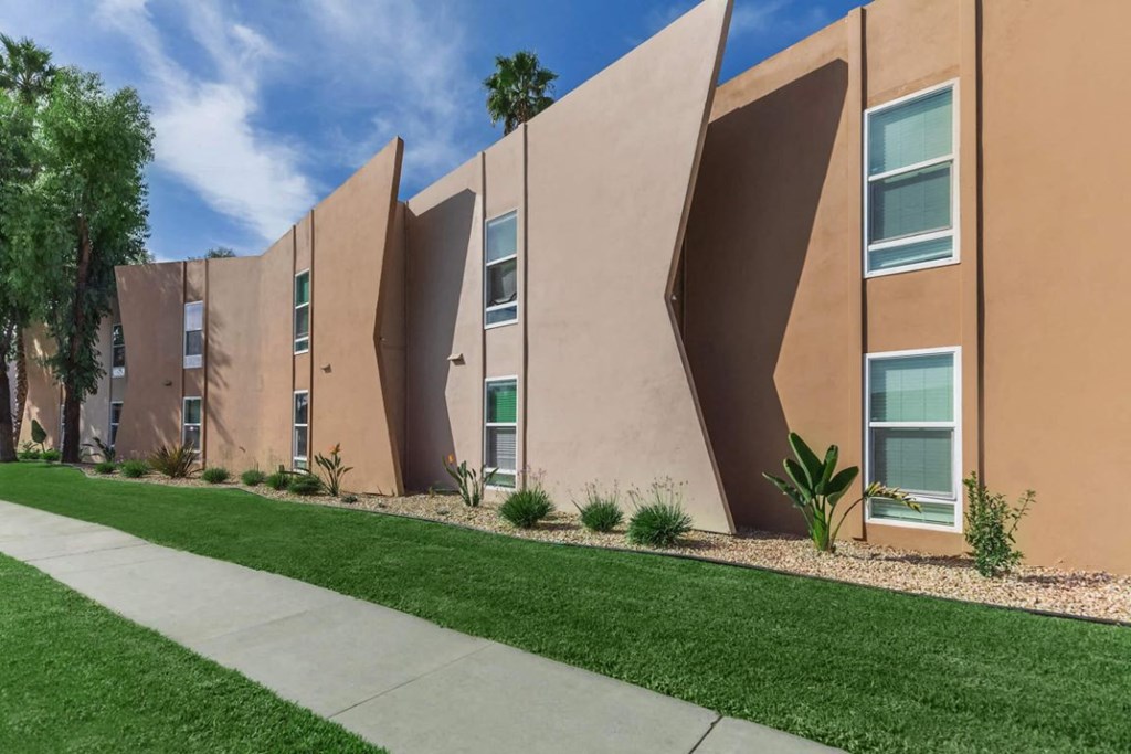 the exterior of a building with grass and a sidewalk