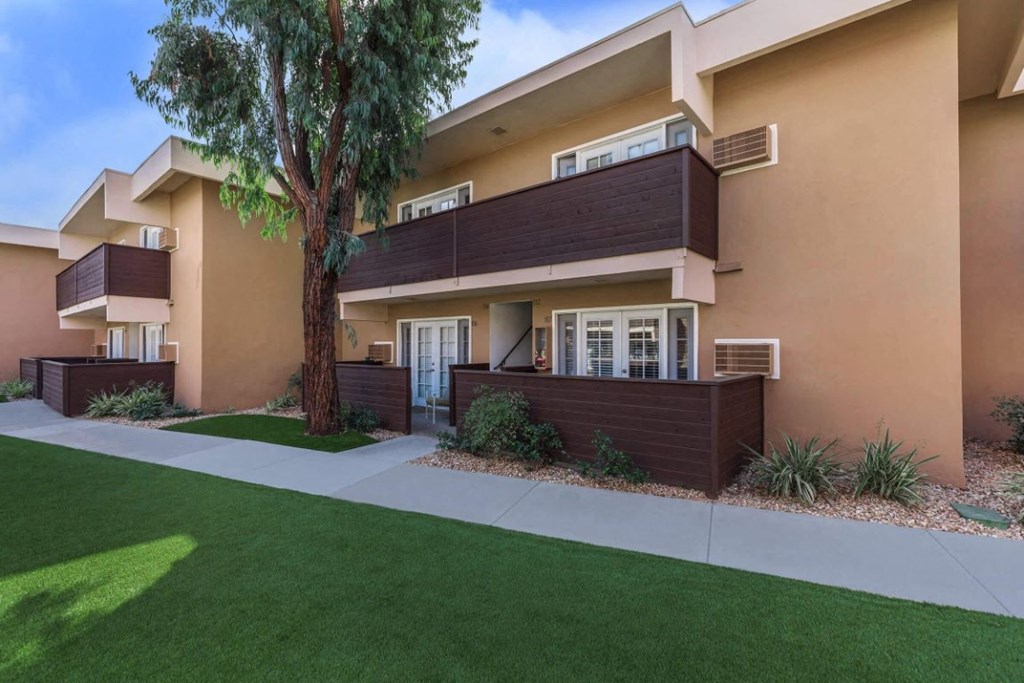 the front of a house with a tree and a sidewalk