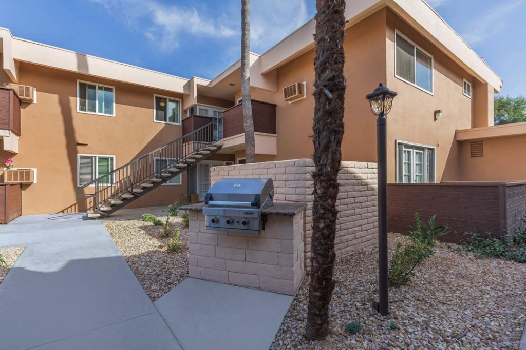 an exterior view of a home with a grill and a sidewalk