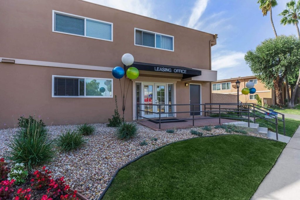 the front entrance of leasing center with balloons and grass