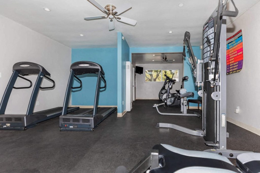 a gym with exercise equipment and a ceiling fan