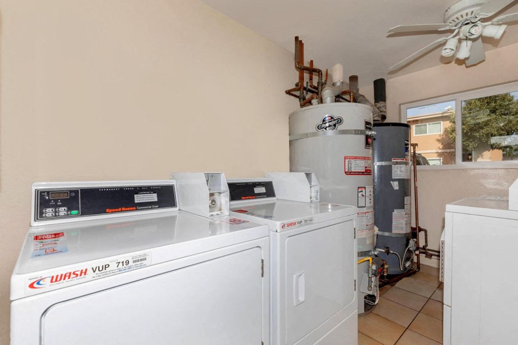 a laundry room with two washing machines and a water heater