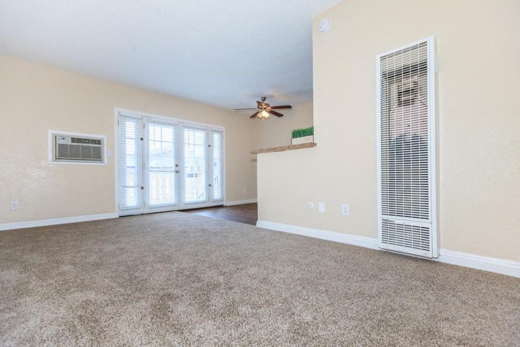 an empty living room with a ceiling fan and a window