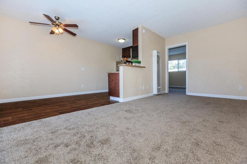 an empty living room with a ceiling fan